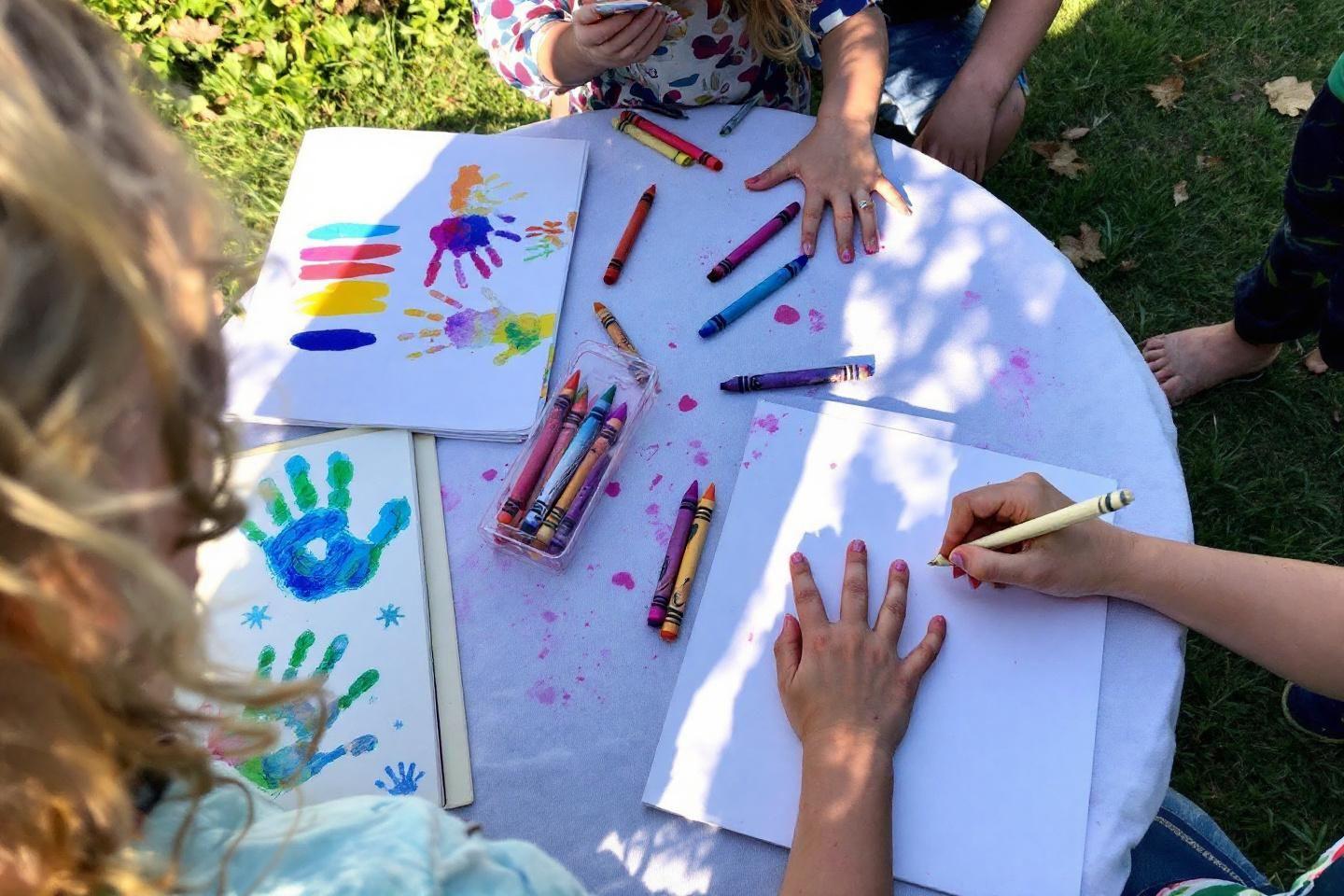 Table blanche avec mains d'enfants dessinant et faisant des empreintes