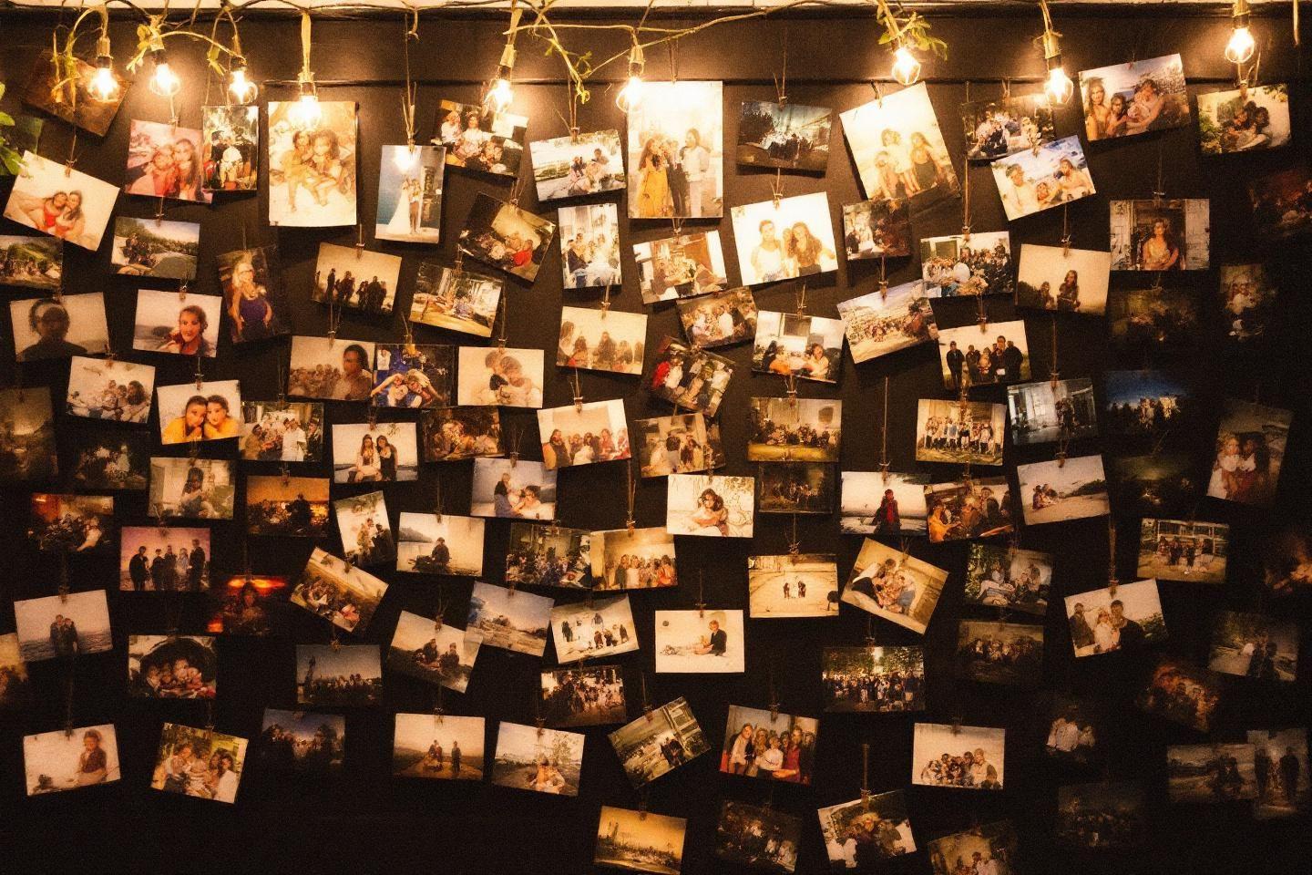 Nombreuses photos accrochées à un mur sombre avec lumières