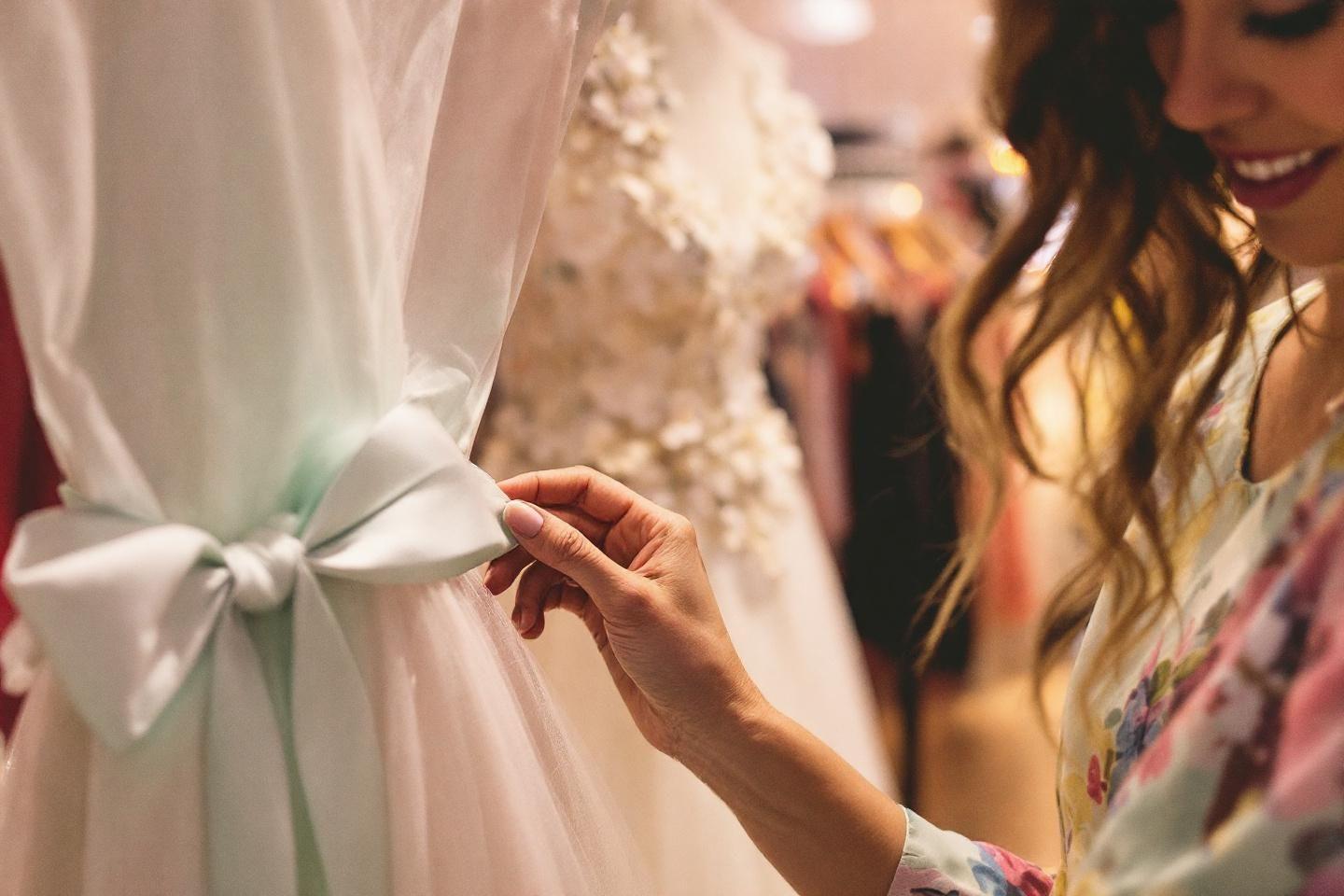 Main touchant une robe blanche avec un ruban vert